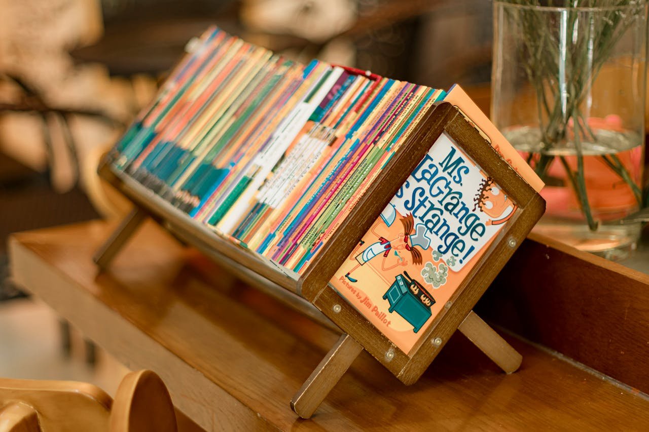 Services A vibrant collection of children's books on a wooden stand indoors.
